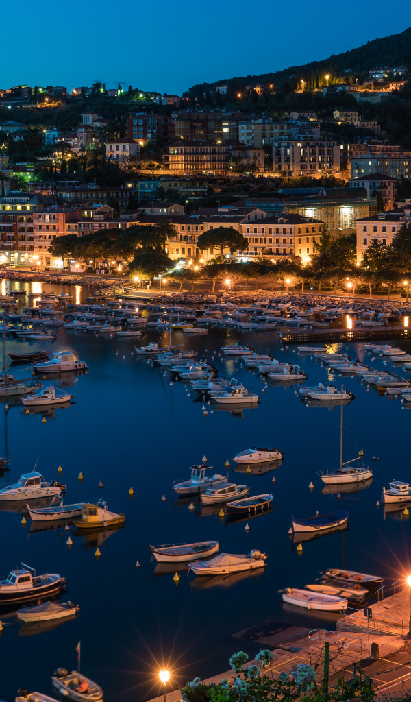 Панорама ночного города и лодки на причале у побережья, Лигурия. Италия