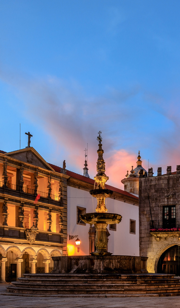 Дома и фонтан на вечерней площади в городе Вьяна, Португалия