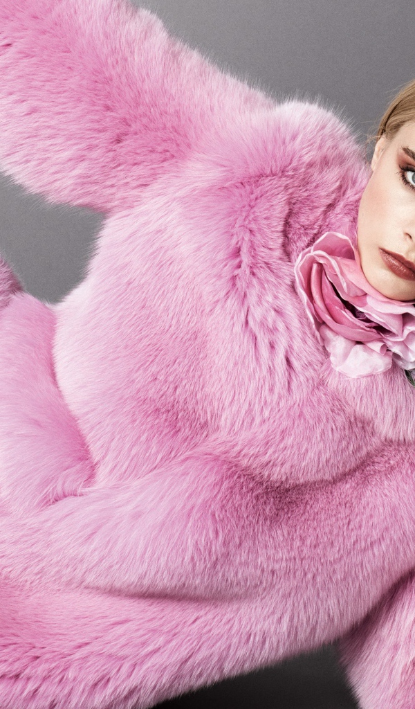 Актриса Кара Делевинь лежит в розовой шубе на сером фоне