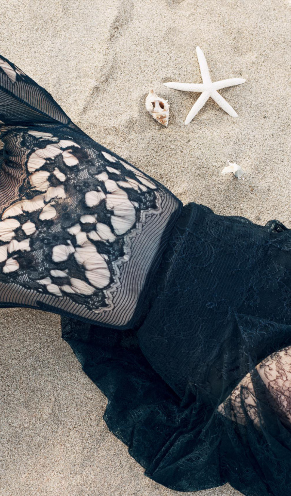 Актриса брюнетка Эмилия Кларк лежит на песке 