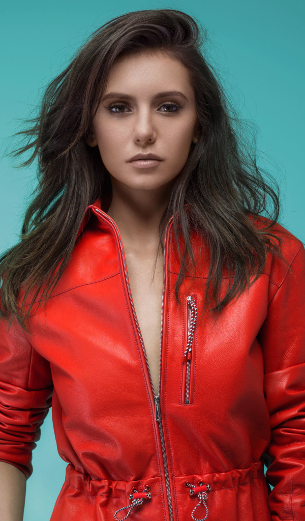 Популярная актриса Нина Добрев в красной куртке на зеленом фоне