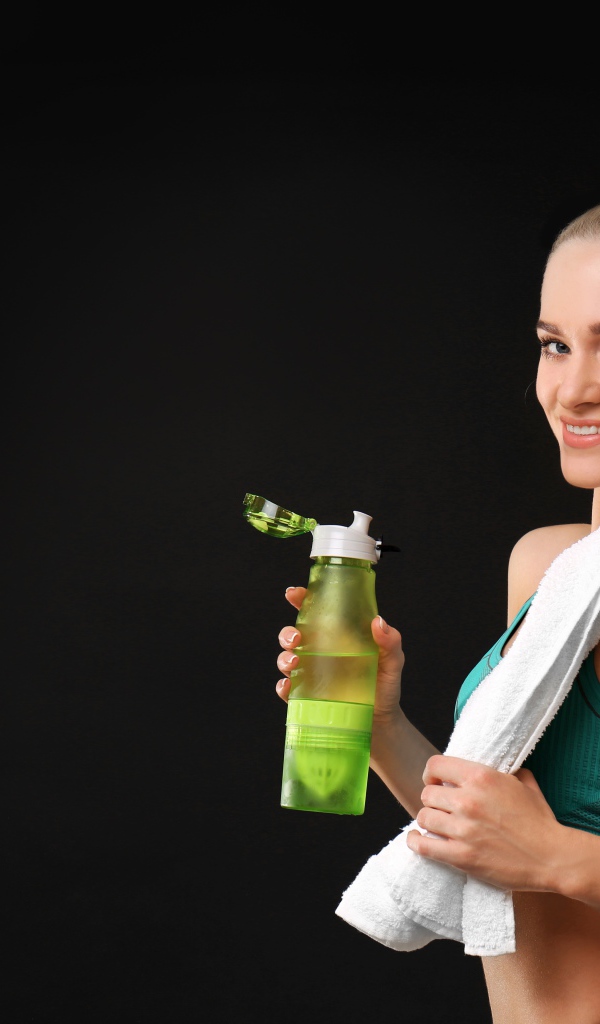 Спортивная девушка блондинка с бутылкой воды в руке