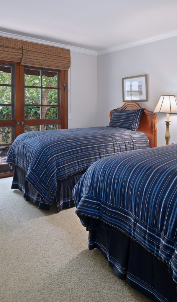 Две большие кровати в спальне с деревянным окном