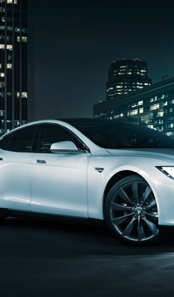 Белый электромобиль Тесла на фоне города 