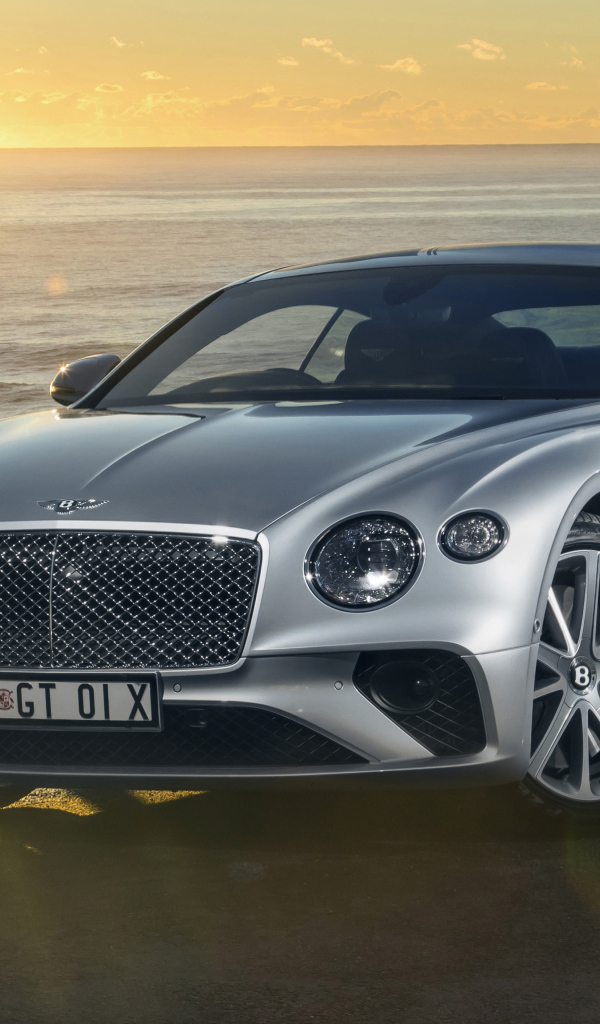 Серебристый Bentley Continental GT 2018 года на фоне моря