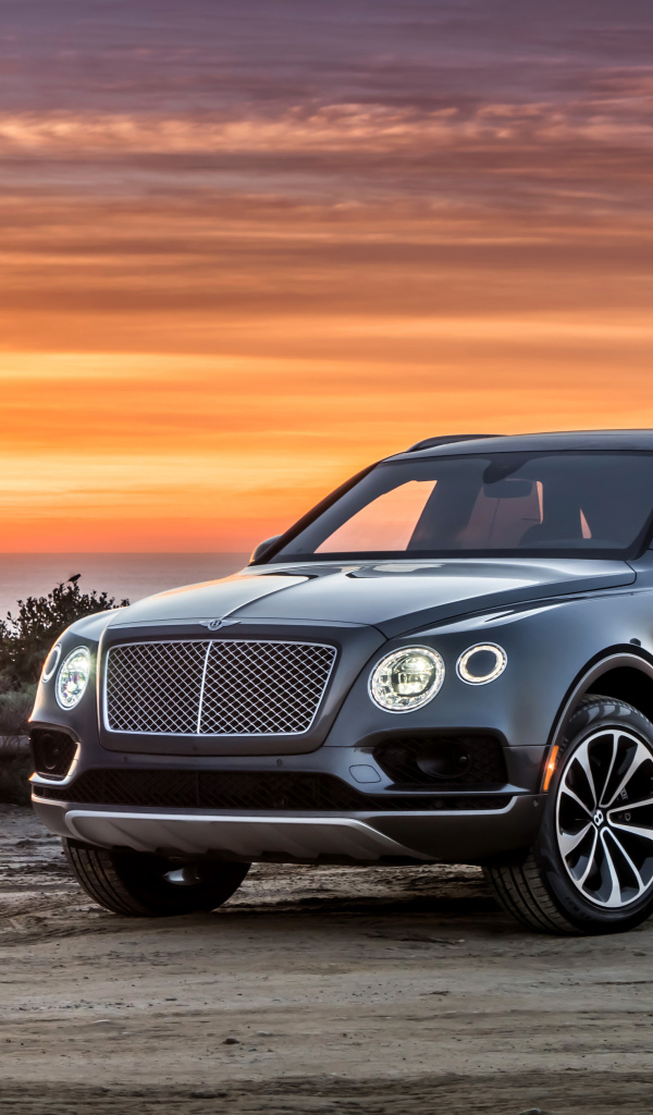 Черный стильный стильный автомобиль Bentley на фоне заката 