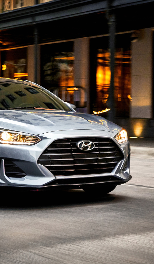 Серебристый автомобиль Hyundai Veloster, 2019 с  включенными фарами 