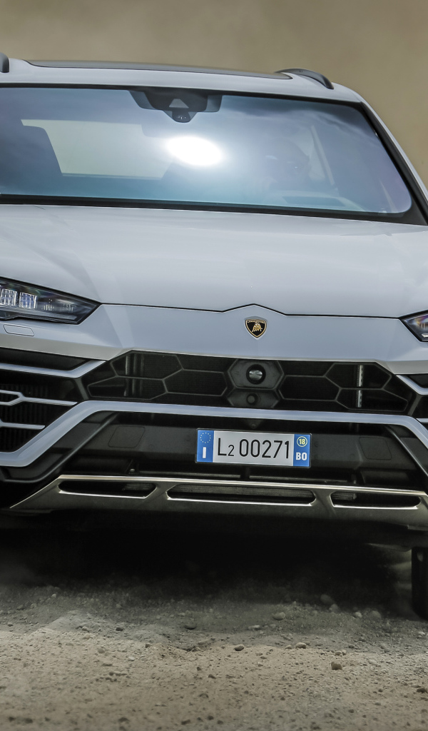 Белый автомобиль Lamborghini Urus  2018 года едет по дороге 