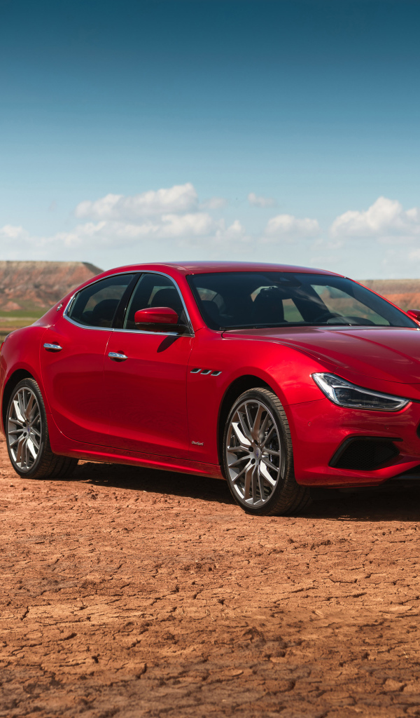 Красный автомобиль Maserati Ghibli на фоне голубого неба