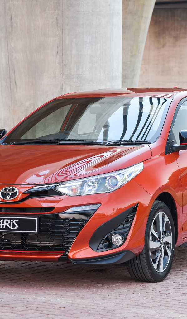 Красный автомобиль Toyota Yaris под мостом 