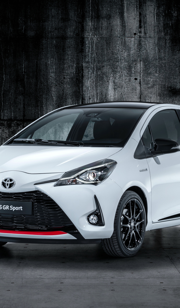 Белый автомобиль Toyota Yaris на сером фоне 