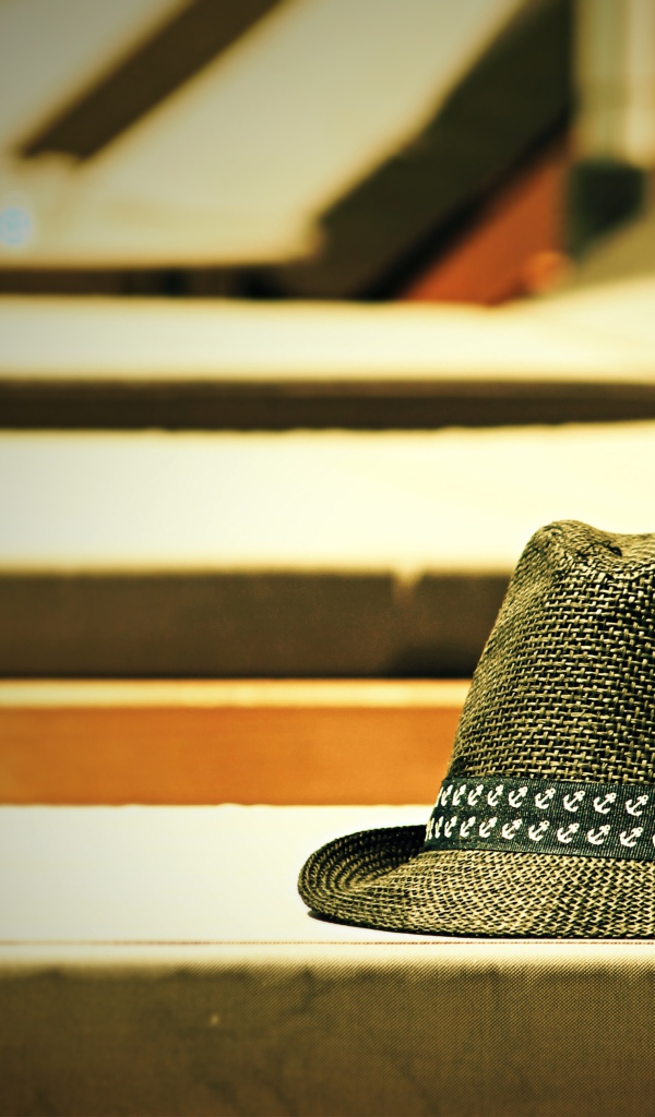 Летняя шляпа лежит на лавке в лучах солнца