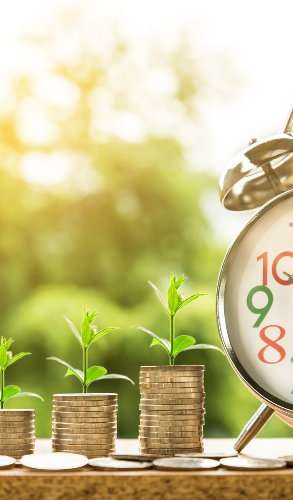 Будильник с монетами с зелеными ростками