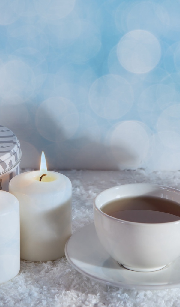 Свечи, чашка чая и фигура лошади на столе 