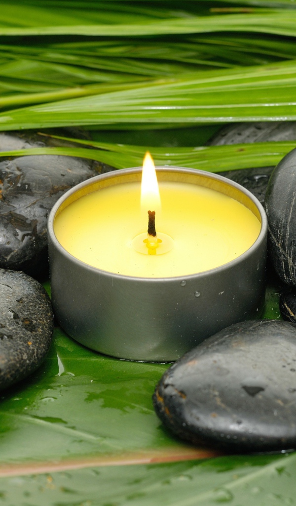 Зажженная свеча и черные камни для SPA