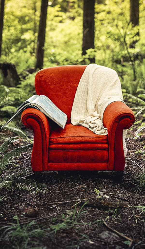 Старое красное кресло с книгой и пледом в лесу 