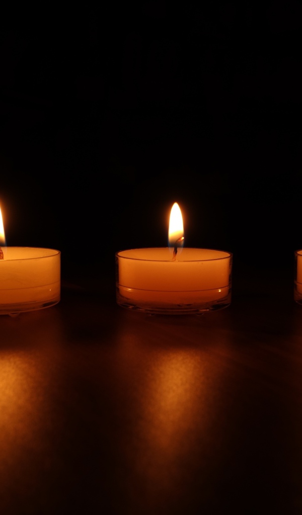 Три зажженные свечи на черном фоне