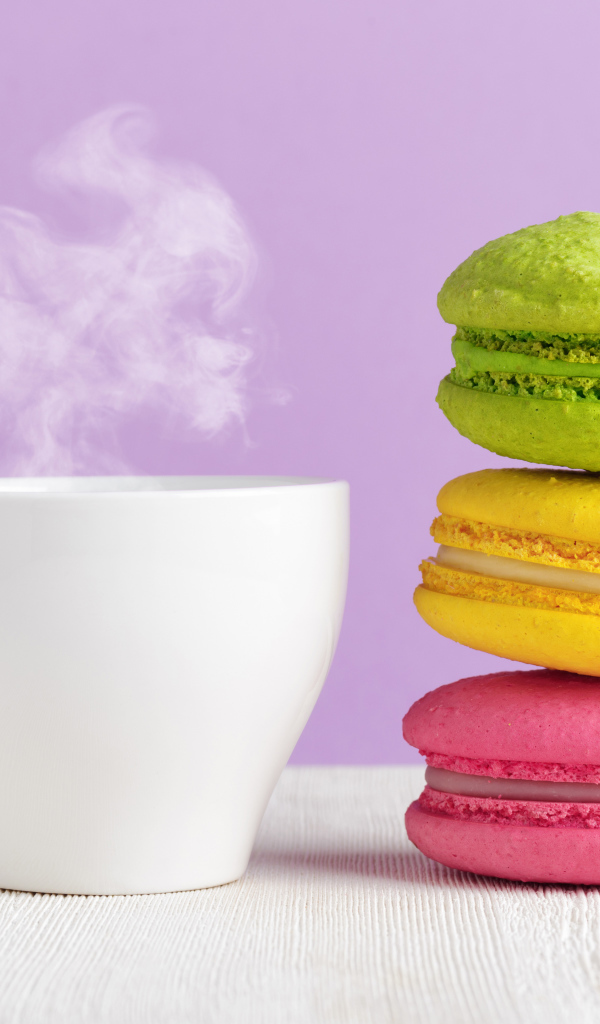A colorful dessert macaroon with a cup of hot coffee on the table