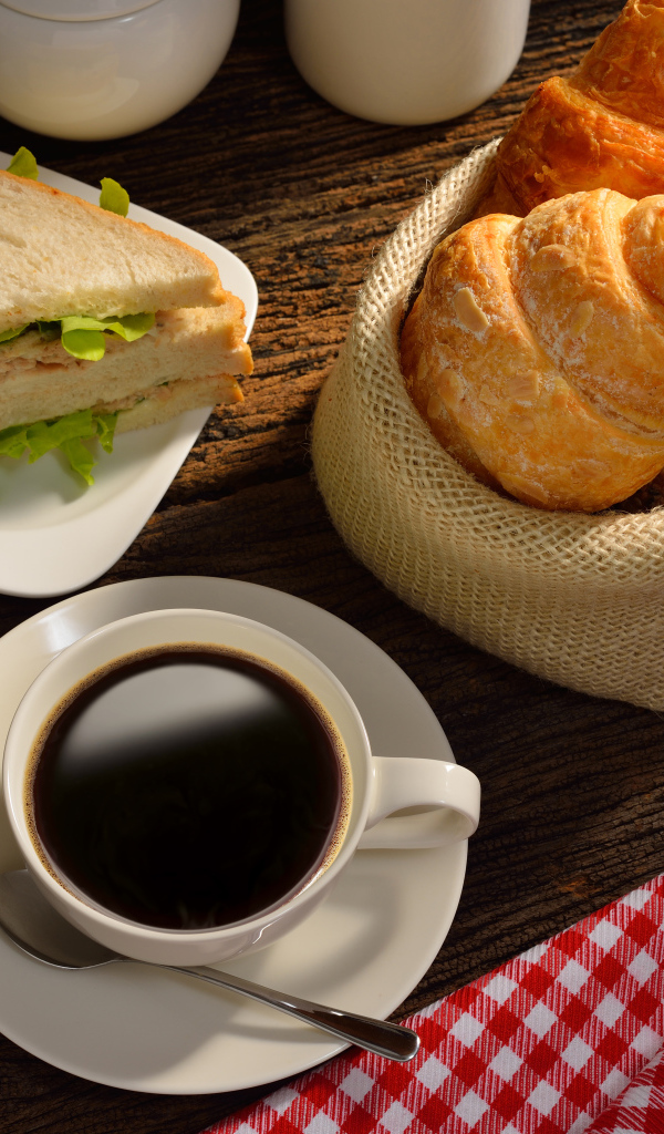 Чашка кофе с круассанами и сендвичем на завтрак