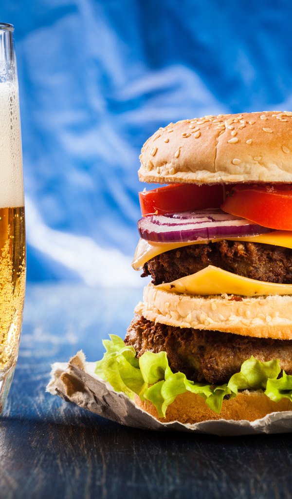 Стакан пива с гамбургером на столе