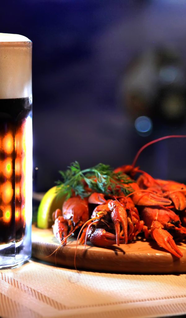 Бокал пива с вареными раками на столе