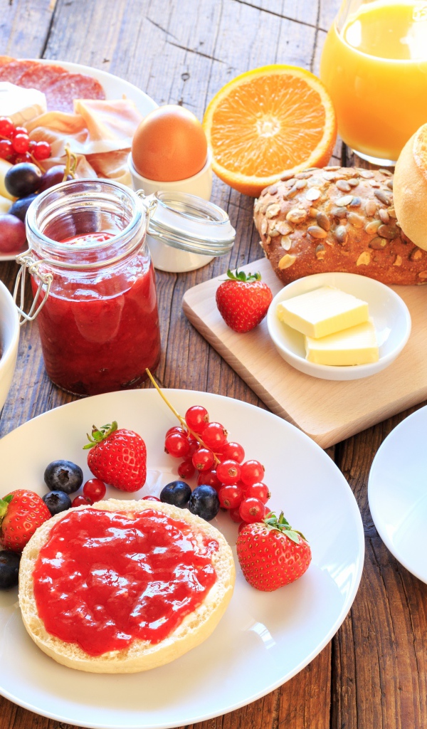 Аппетитный завтрак на столе с бутербродами, кофе и ягодами