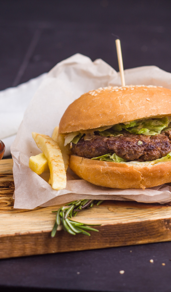 Аппетитный гамбургер с картофелем фри и кетчупом на столе