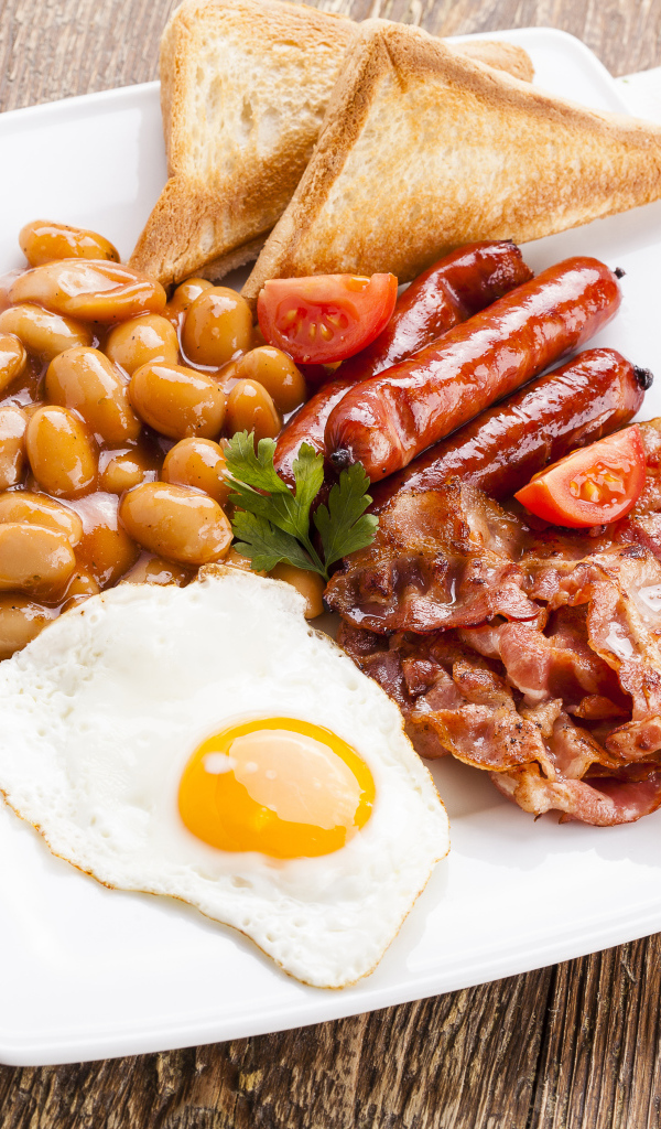 Бекон, яичница, фасоль и сосиски на тарелке к завтраку 