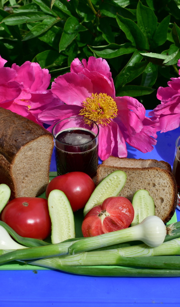 Черный хлеб, овощи и вино на фоне розовых пионов 