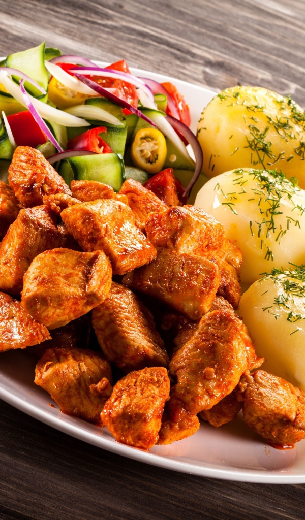 Вареный картофель с мясом и салатом на тарелке