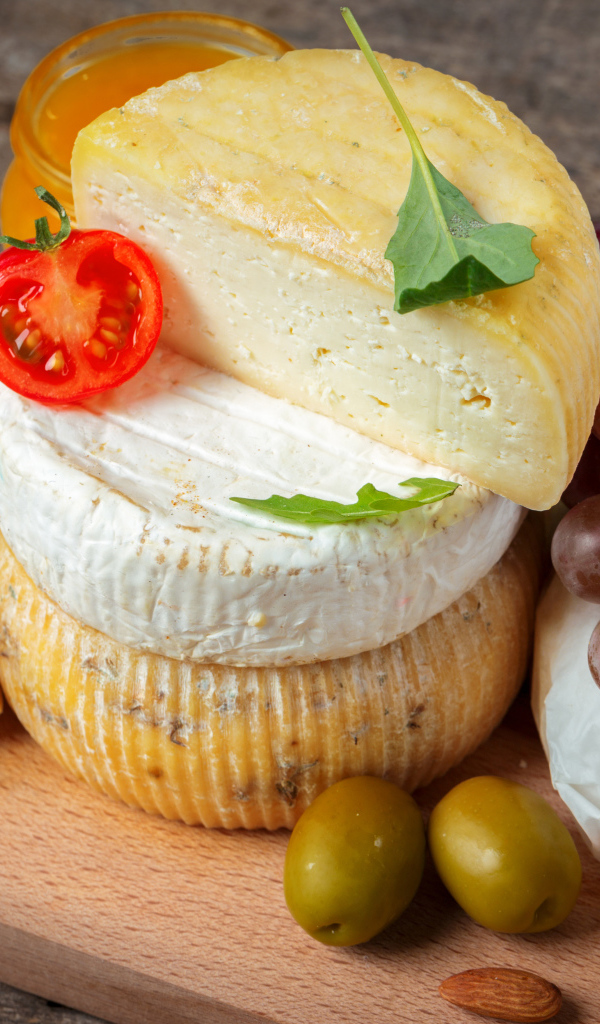 Сыр на разделочной доске с виноградом и оливками