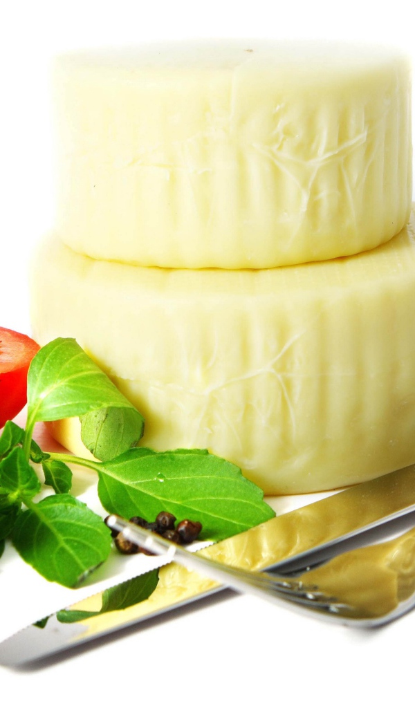Сыр с помидором, столовыми приборами, оливками и зеленью на белом фоне