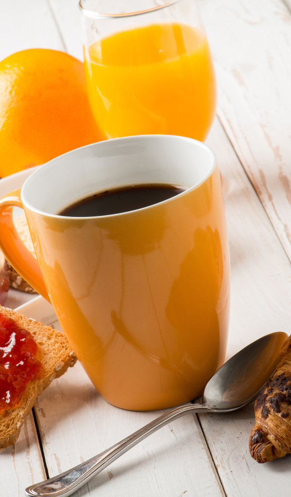 Кофе на деревянном столе с круассанами, соком и джемом 