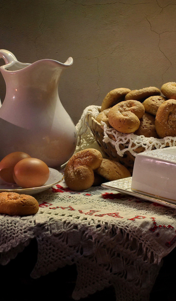 Вареные яйца на столе с кувшином, выпечкой и масленкой 