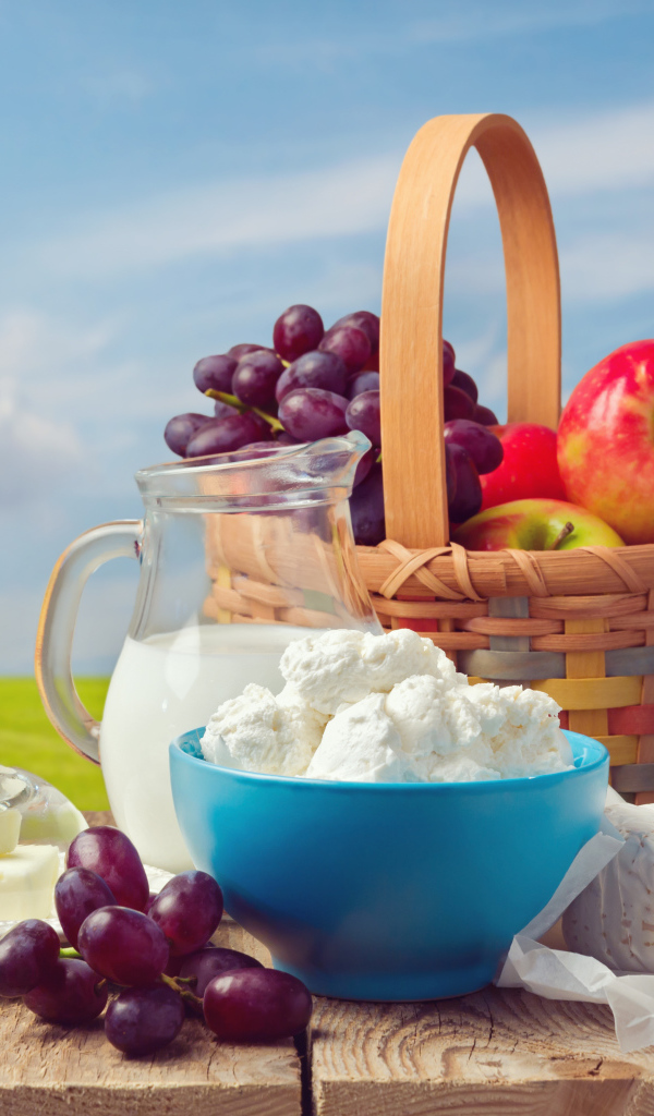 Творог с молоком на столе с виноградом и яблоками 