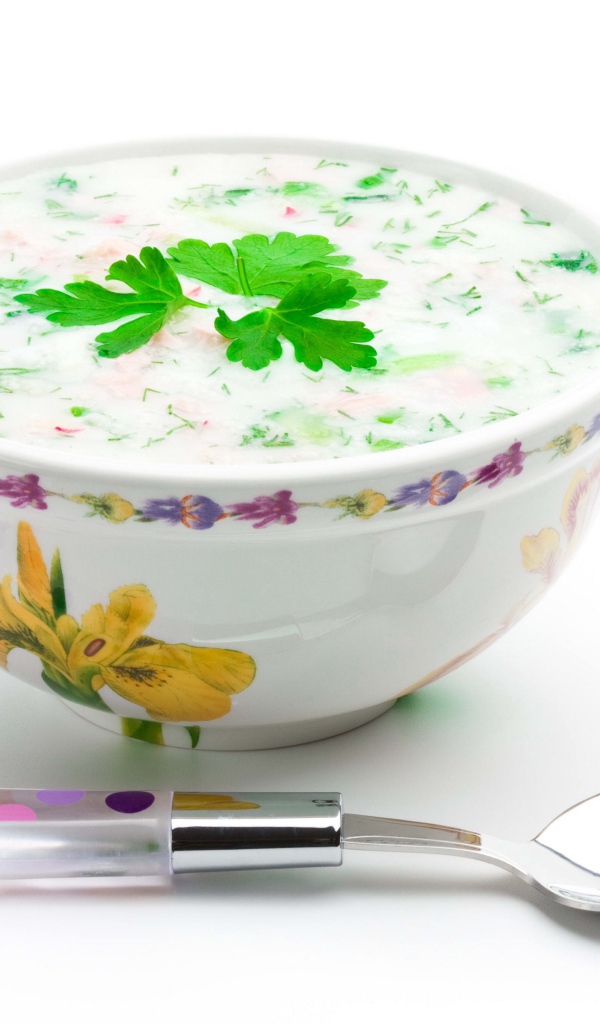 Аппетитная вкусная окрошка в тарелке на белом фоне с ложкой 