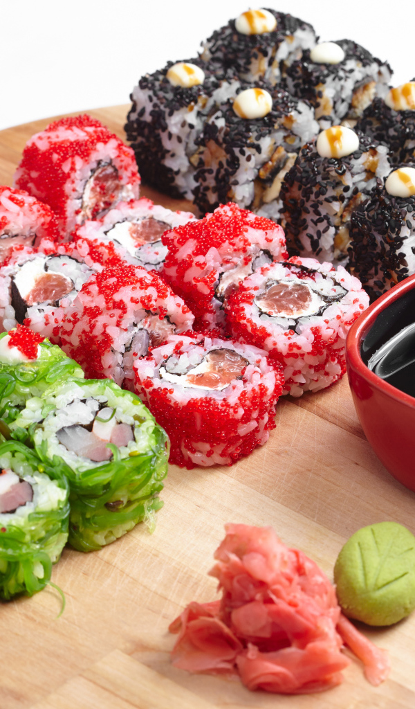 Разные аппетитные суши на деревянной доске с соевым соусом