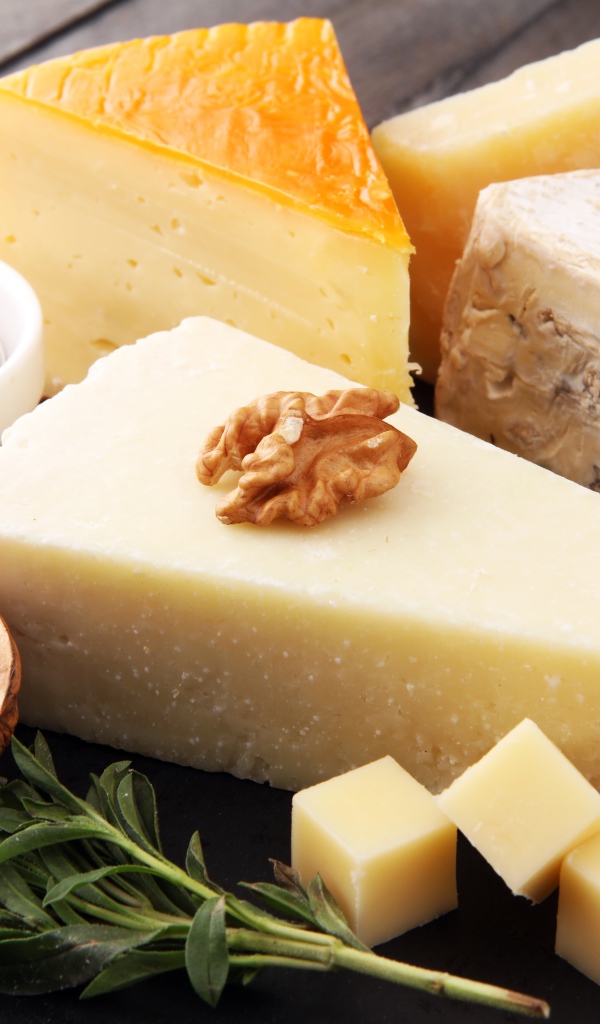 Разные виды сыра на столе с медом и грецкими орехами