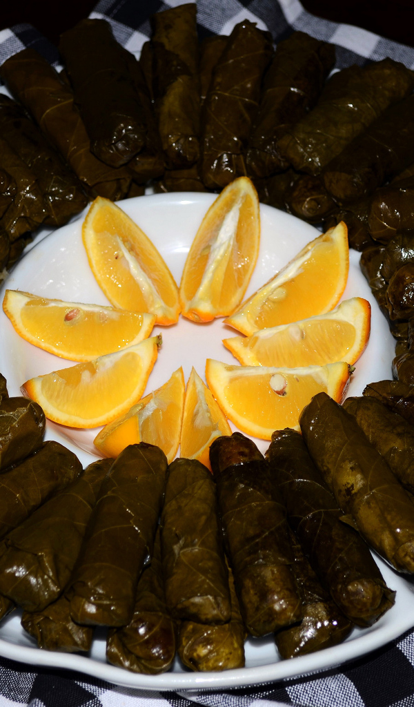 Долма на большом блюде с кусочками апельсина 