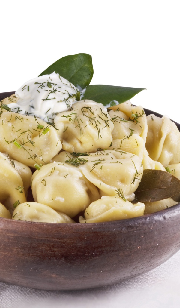 Пельмени в миске на белом фоне с ложкой 