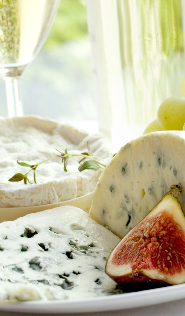 Дорогой сыр с плесенью на тарелке с инжиром и белым виноградом