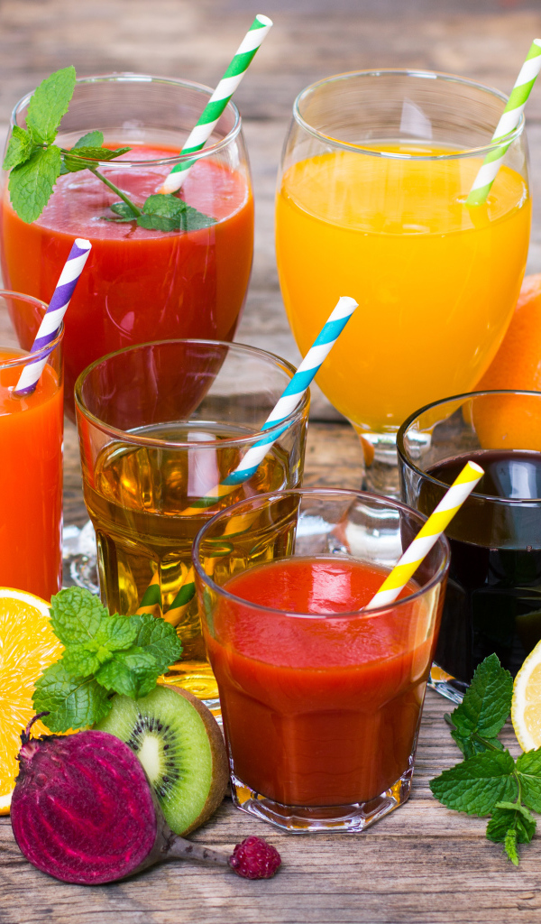 Свежевыжатые соки на столе с овощами и фруктами