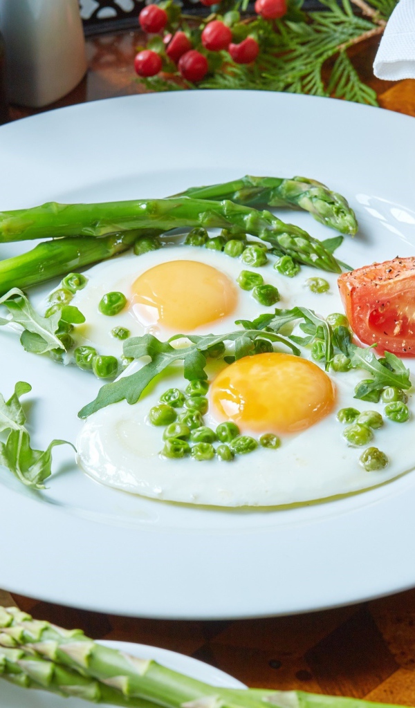 Fried eggs for breakfast with green peas and asparagus