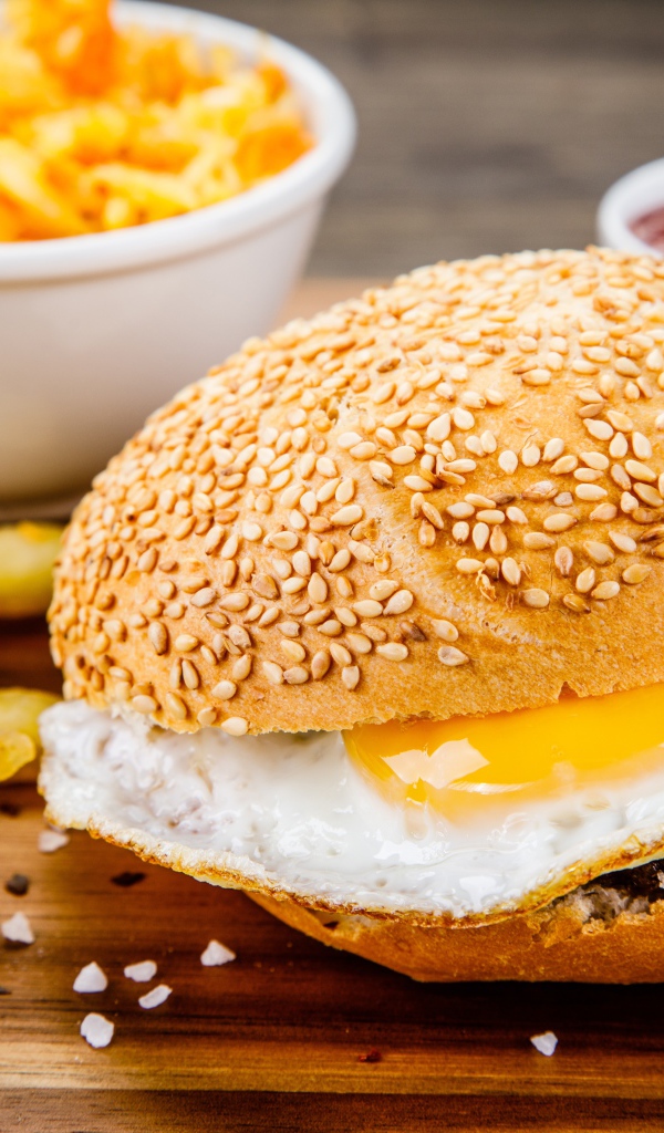 Гамбургер с яичницей на столе с картофелем фри и соусом