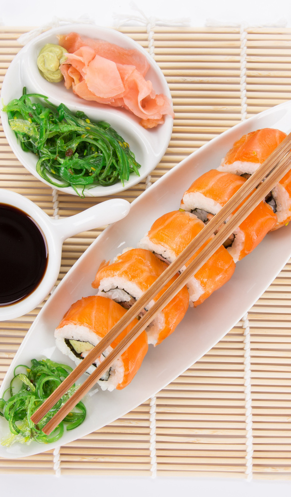 Японские суши на столе с соевым соусом и имбирем с салатом