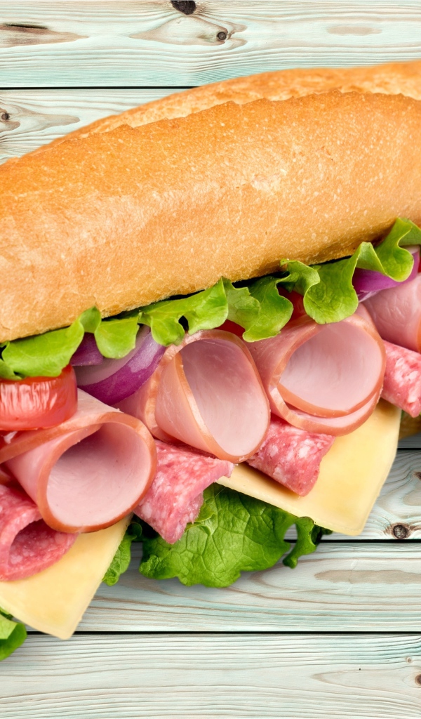 Большой бутерброд с колбасой, сыром и листьями салата