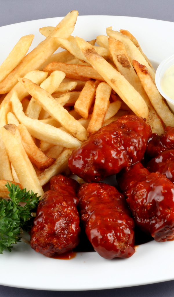 Тефтели в соусе с картофелем фри и петрушкой на тарелке