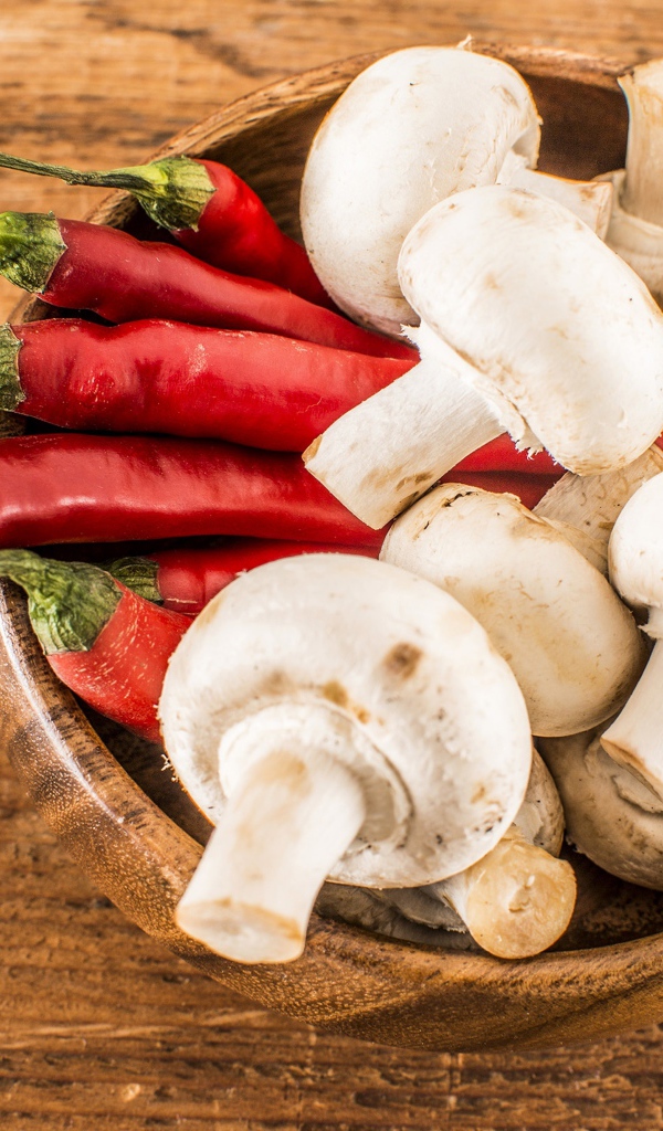 Грибы шампиньоны в деревянной миске с красным перцем