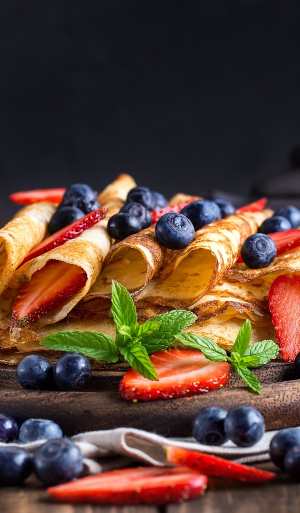 Блинчики с ягодами черники и клубники на столе