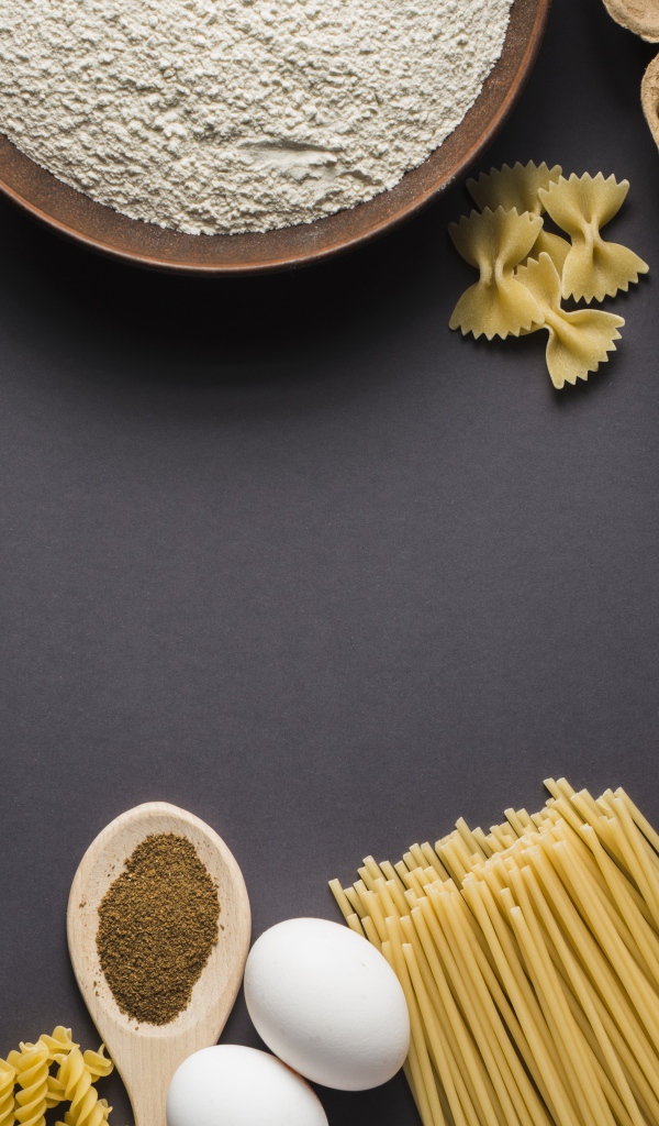 Паста, яйца, специи и помидоры на сером фоне